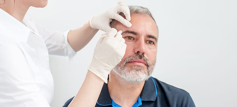 image of a dermatologist inspecting the skin on a patient's face near the eyebrow