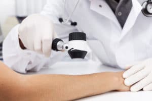 image of a dermatologist inspecting a patient's arm