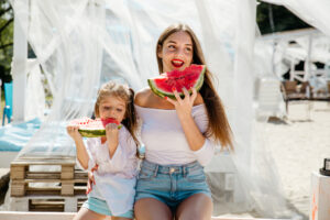 Mom and daughter outside enjoying watermelon in sunny Miami for the 4th of July