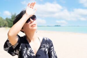 Woman on beach shielding eyes from the sun